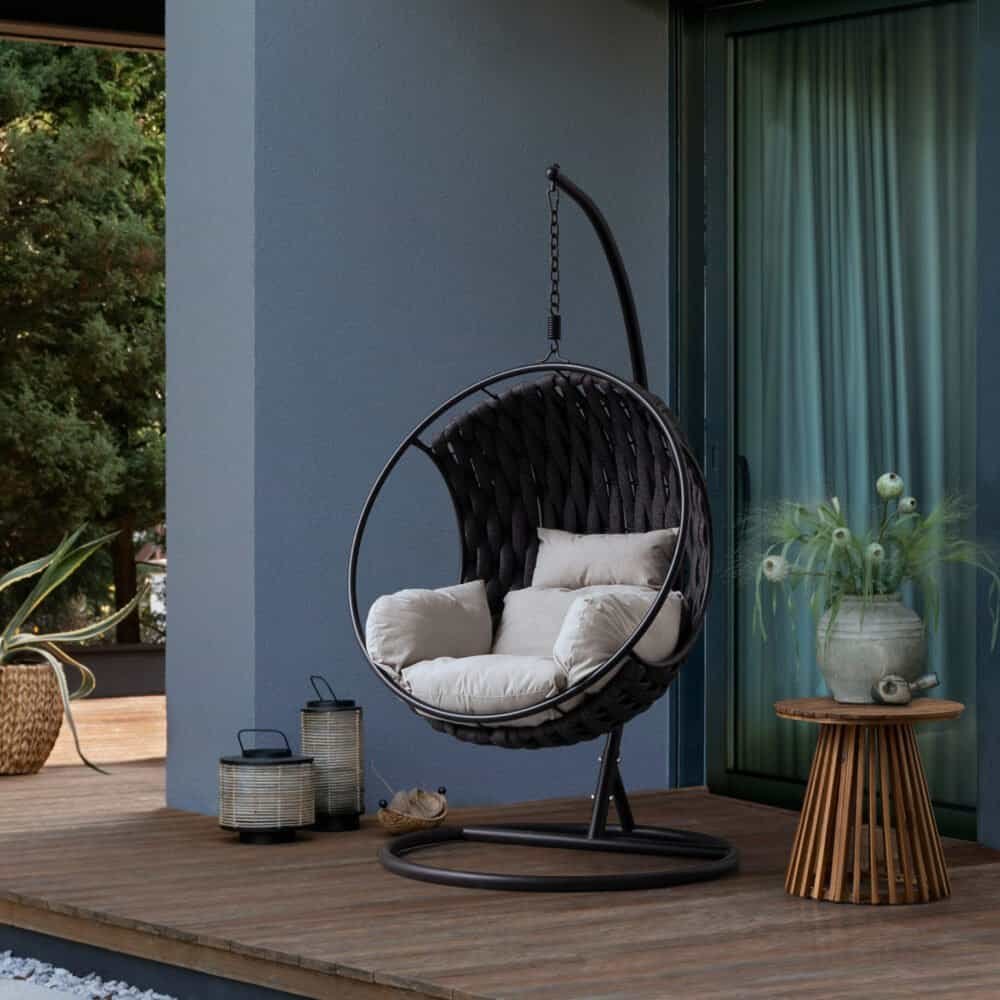 Sedia sospesa in metallo nero con cuscini per relax in giardino o terrazza.