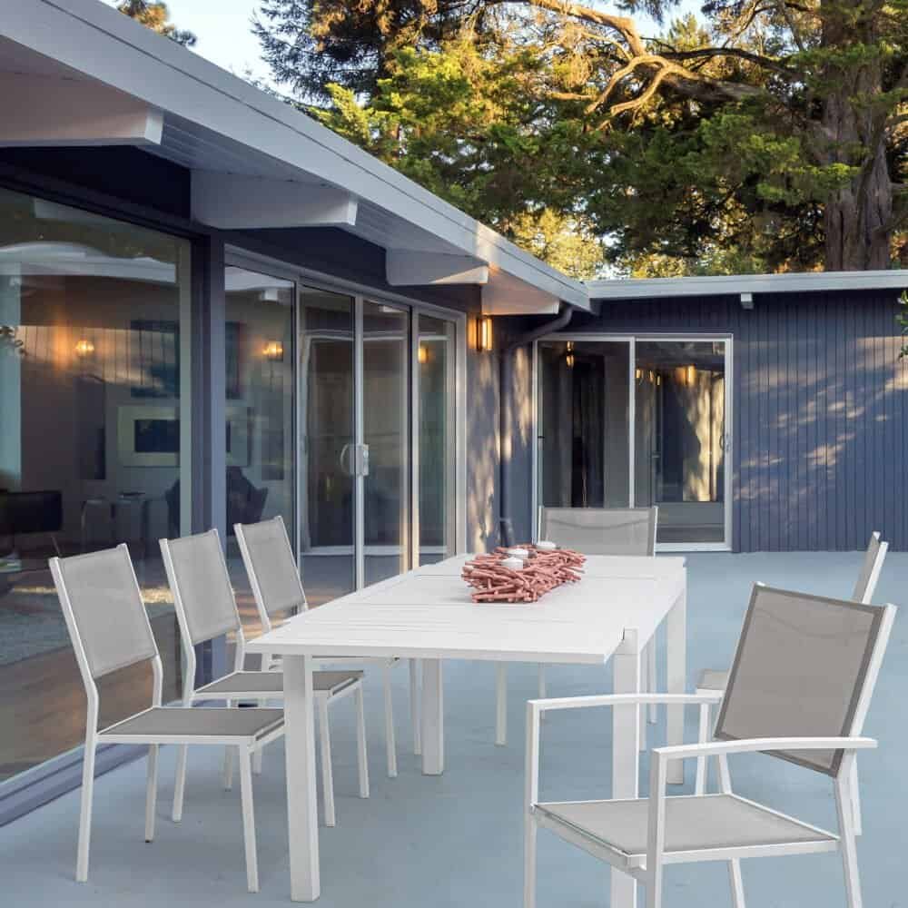 Immagine di un'area patio moderna con tavolo e sedie in stile contemporaneo, immersa nel verde e circondata da grandi alberi.