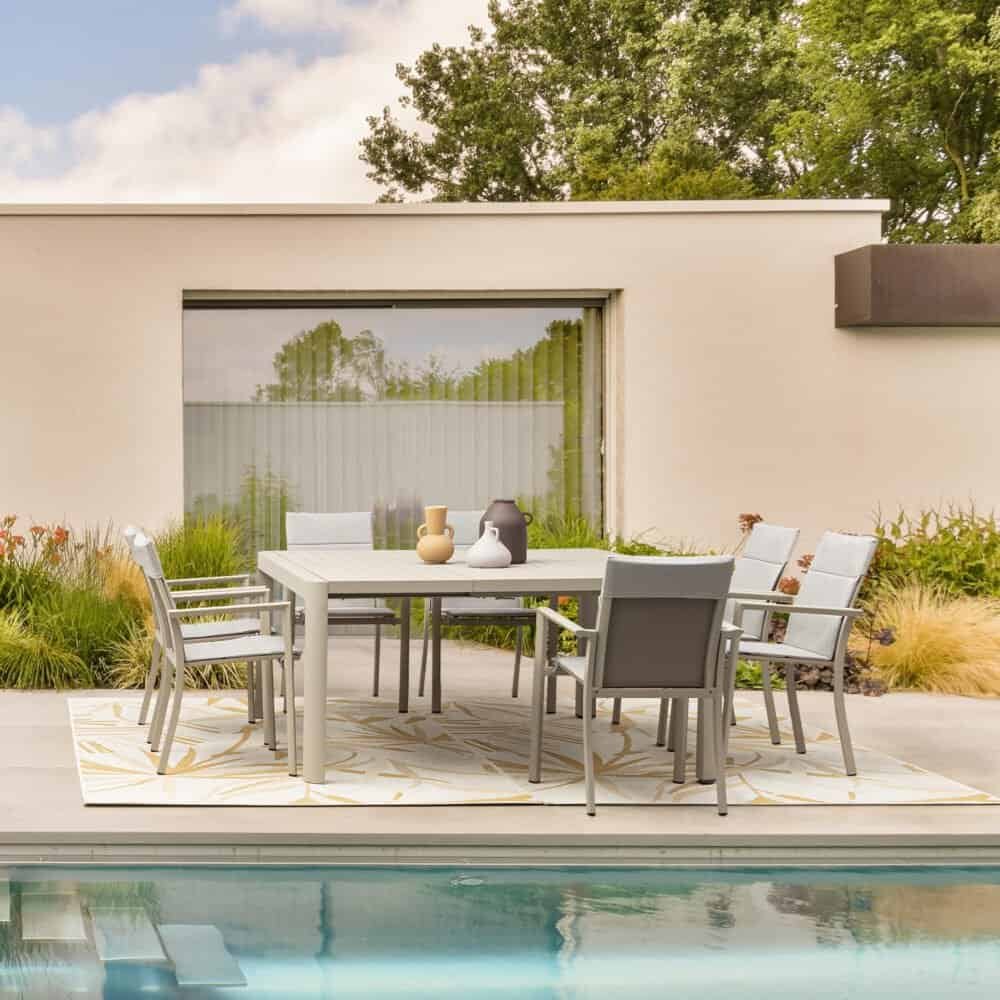 Tavolo da giardino con sedie in ambientazione moderna, terrazza e piscina.
