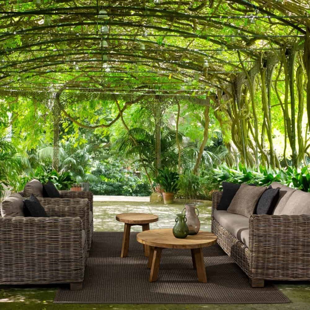 Oasi di relax in giardino con divani in rattan e atmosfera naturale verdeggiante.