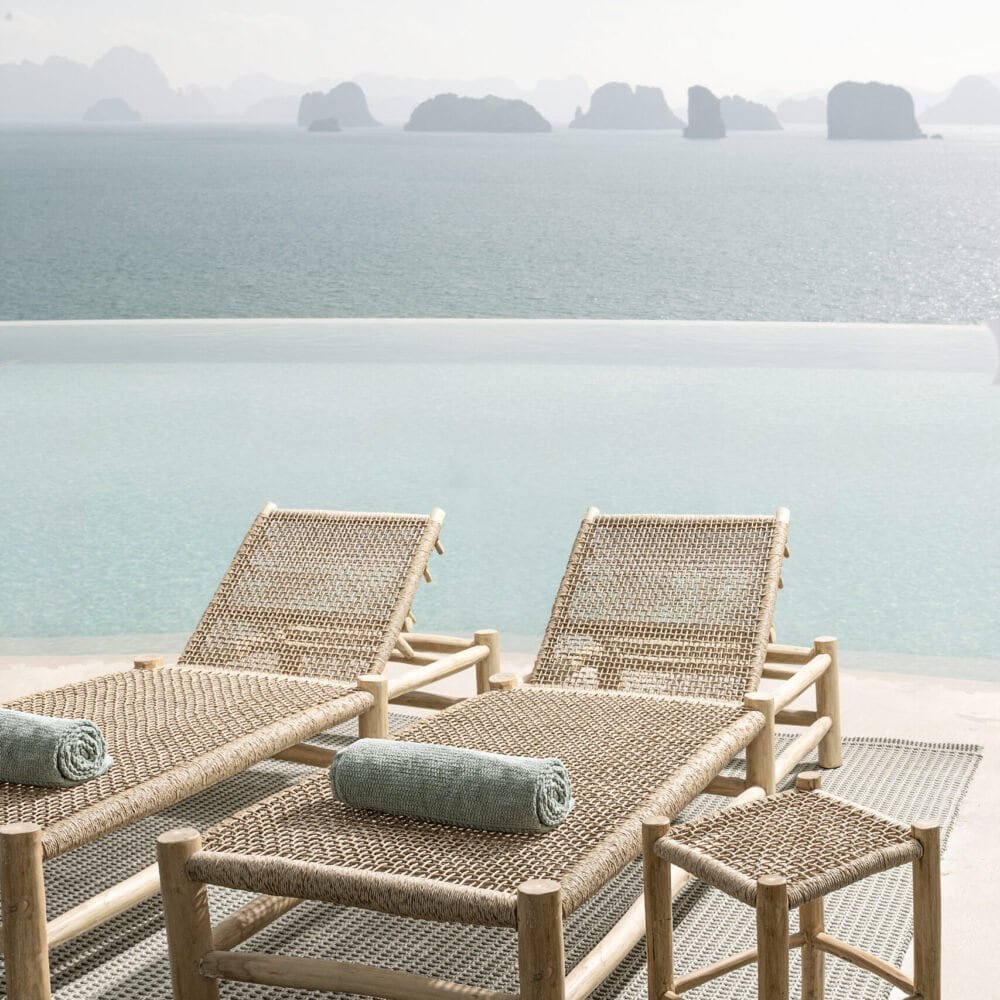 Sdraio in rattan vicino alla piscina con vista mare, perfette per il relax estivo.