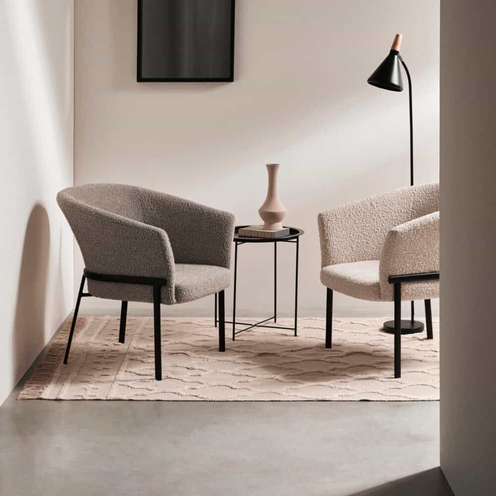 Sedia moderna in tessuto beige con struttura in metallo nero, perfetta per ambienti di design.