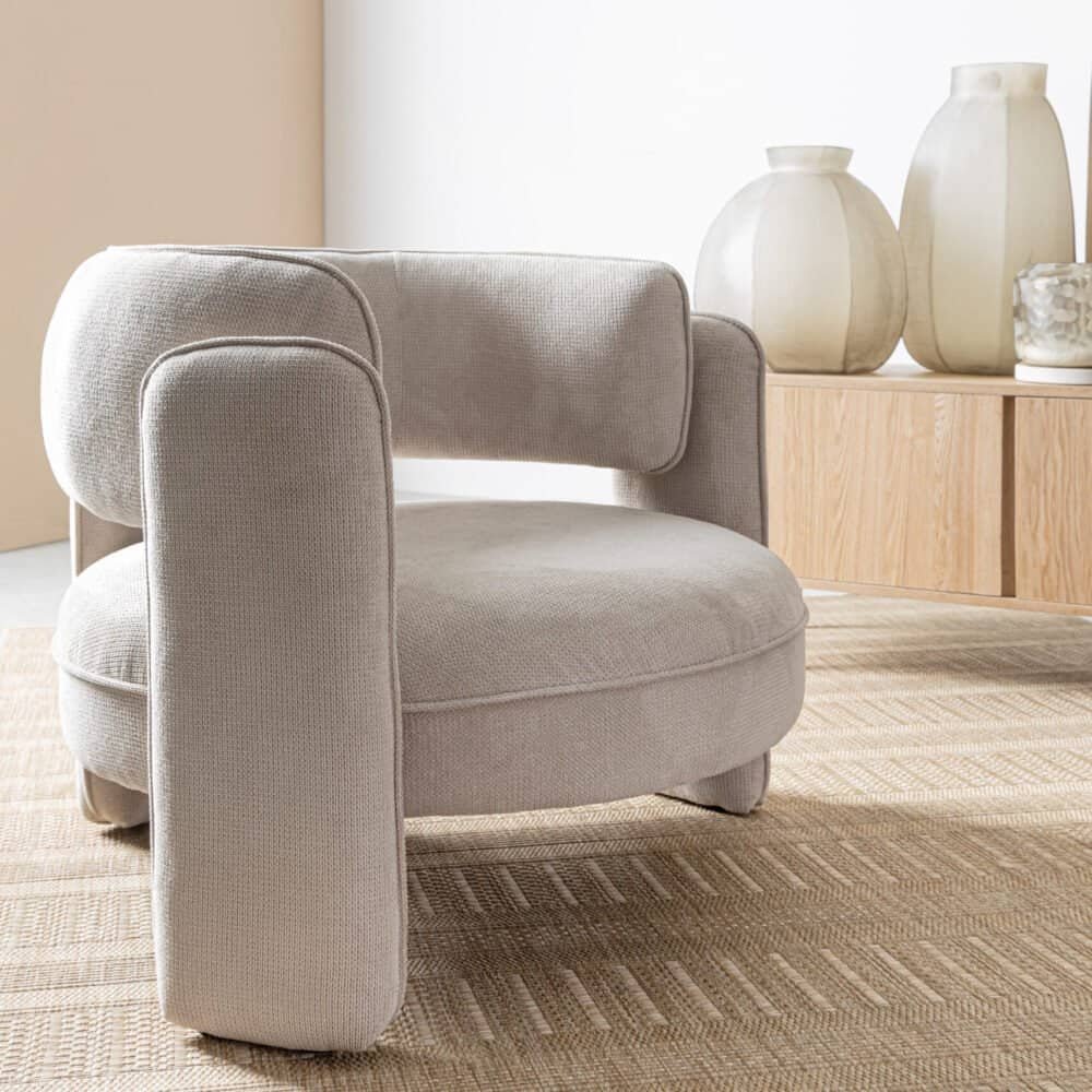 Poltrona in tessuto beige con design minimalista e comfort, perfetta per ambienti eleganti.
