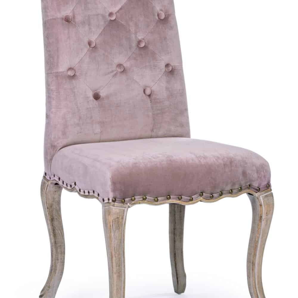 Elegante sedia in velluto rosa con dettagli artigianali e struttura in legno sbiancato, perfetta per arredi raffinati.
