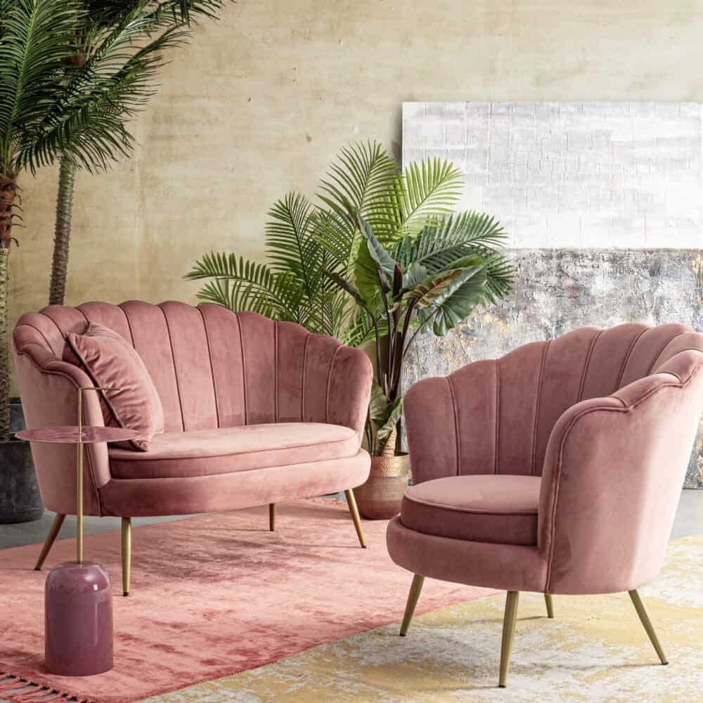 Alt text: Divani in velluto rosa con mobili di design, piante verdi, atmosfera di lusso moderna.