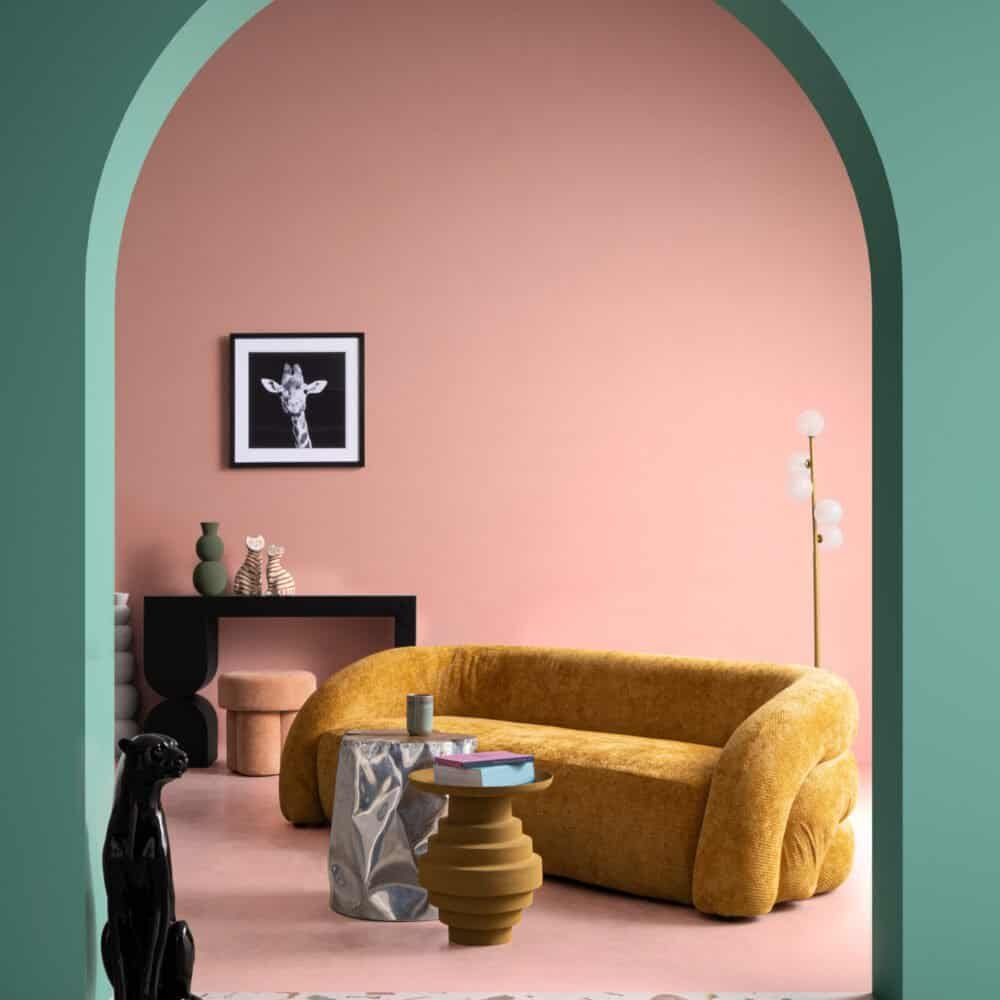 Soggiorno moderno con divano giallo, pareti rosa e dettagli di design. Perfetto per arredi alla moda e di tendenza.