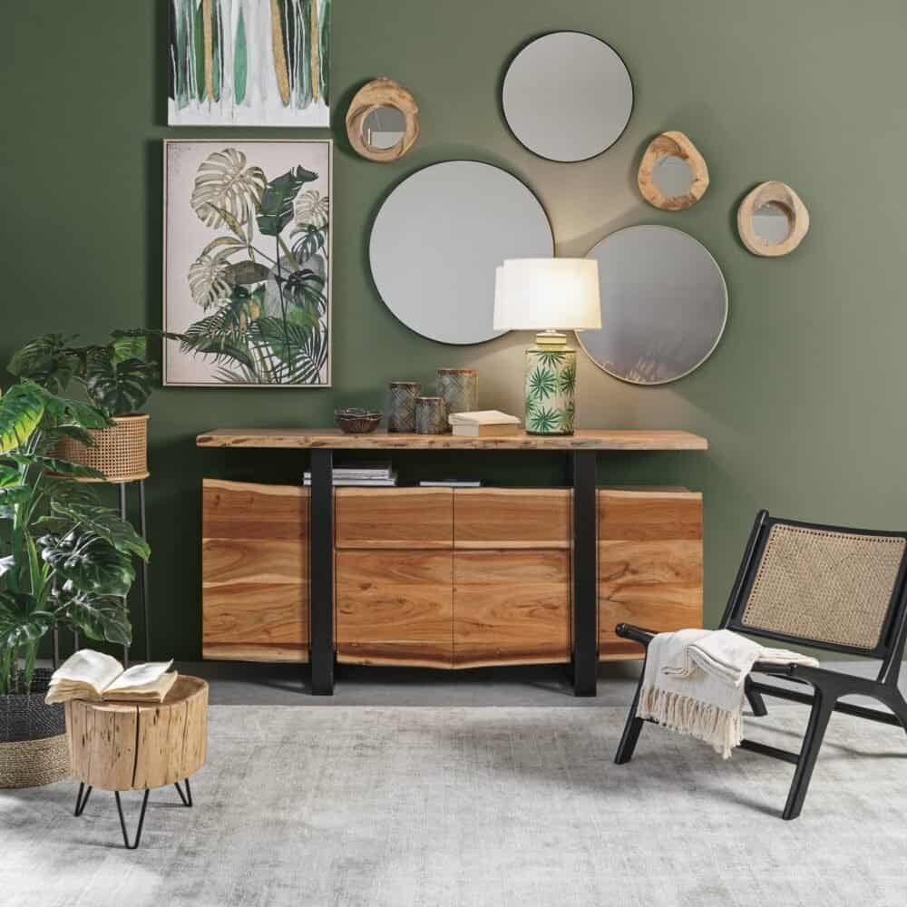 Specchio rotondo e quadri con motivi botanici su parete verde.