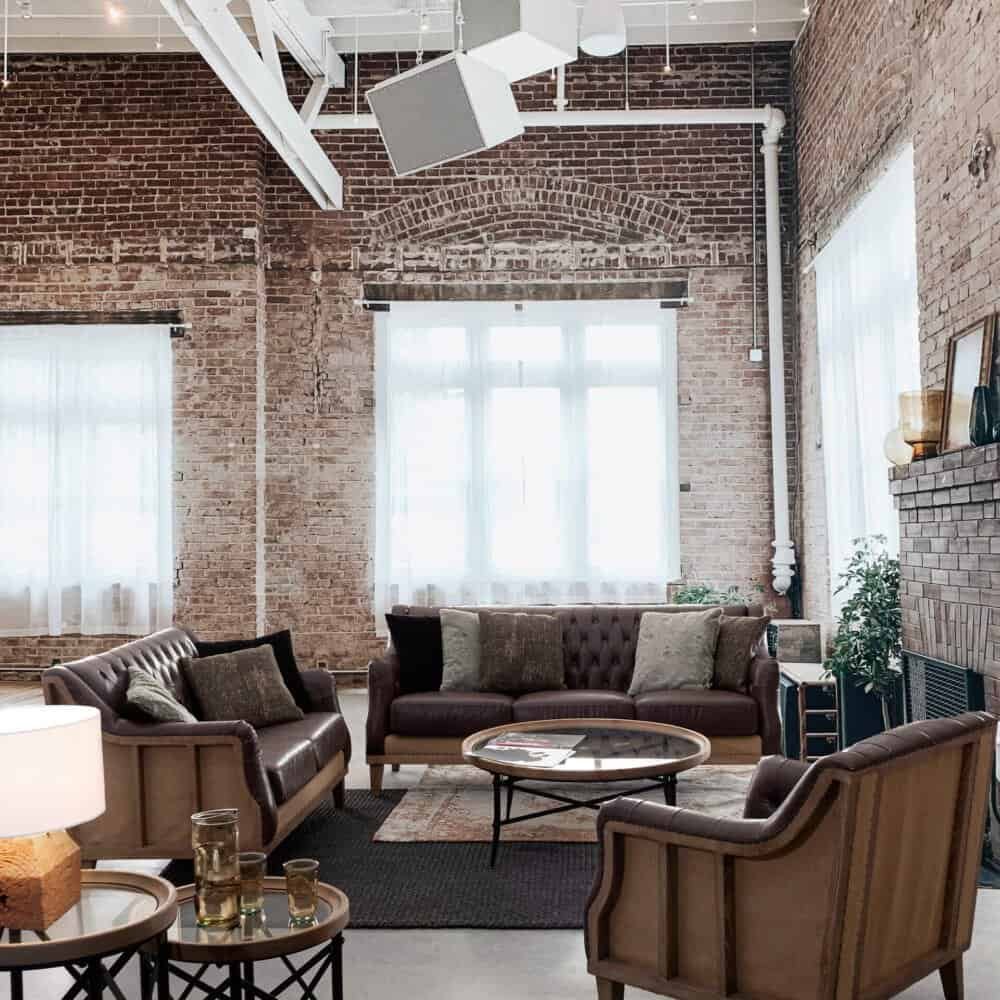 Spazi lounge stile industriale con comode sedie in pelle, divano, grandi finestre, atmosfera moderna, design elegante.