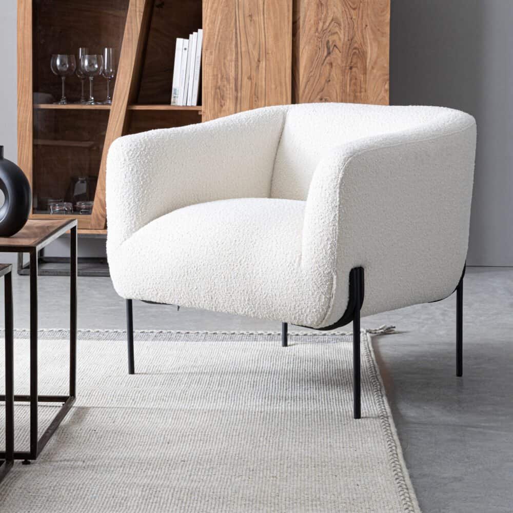 Poltrona bianca in tessuto boucle con design elegante e gambe sottili nere.