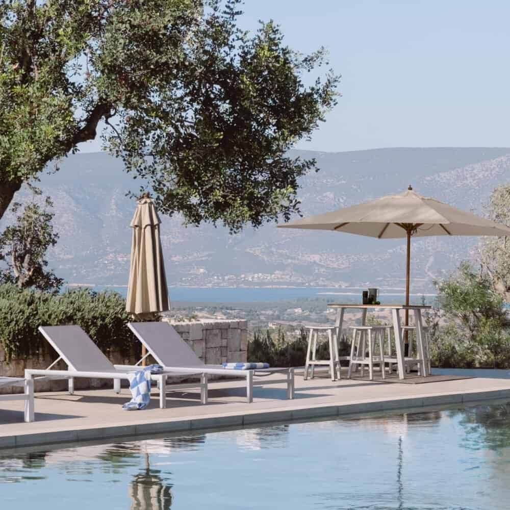 Piscina relax con ombrelloni e sdraio, vista panoramica sulle montagne e sul mare, ambiente tranquillo e in stile mediterraneo.