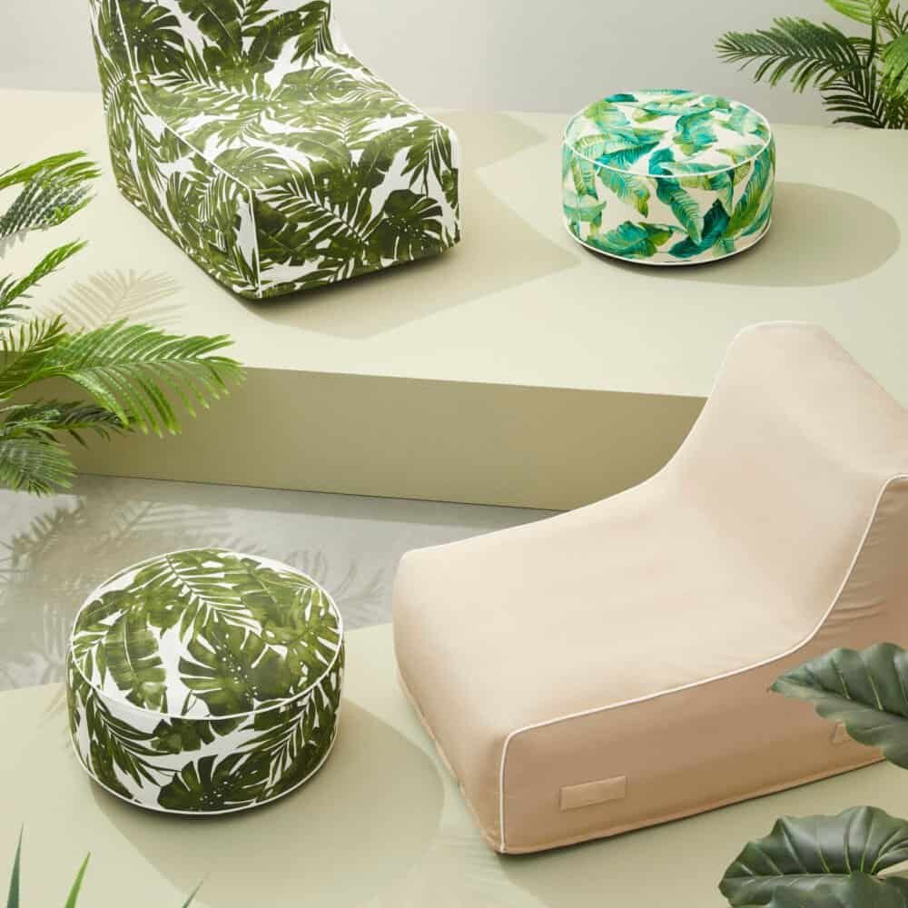 Poltrona e pouf con stampa foglie tropicali, arredamento contemporaneo e atmosfera naturale.