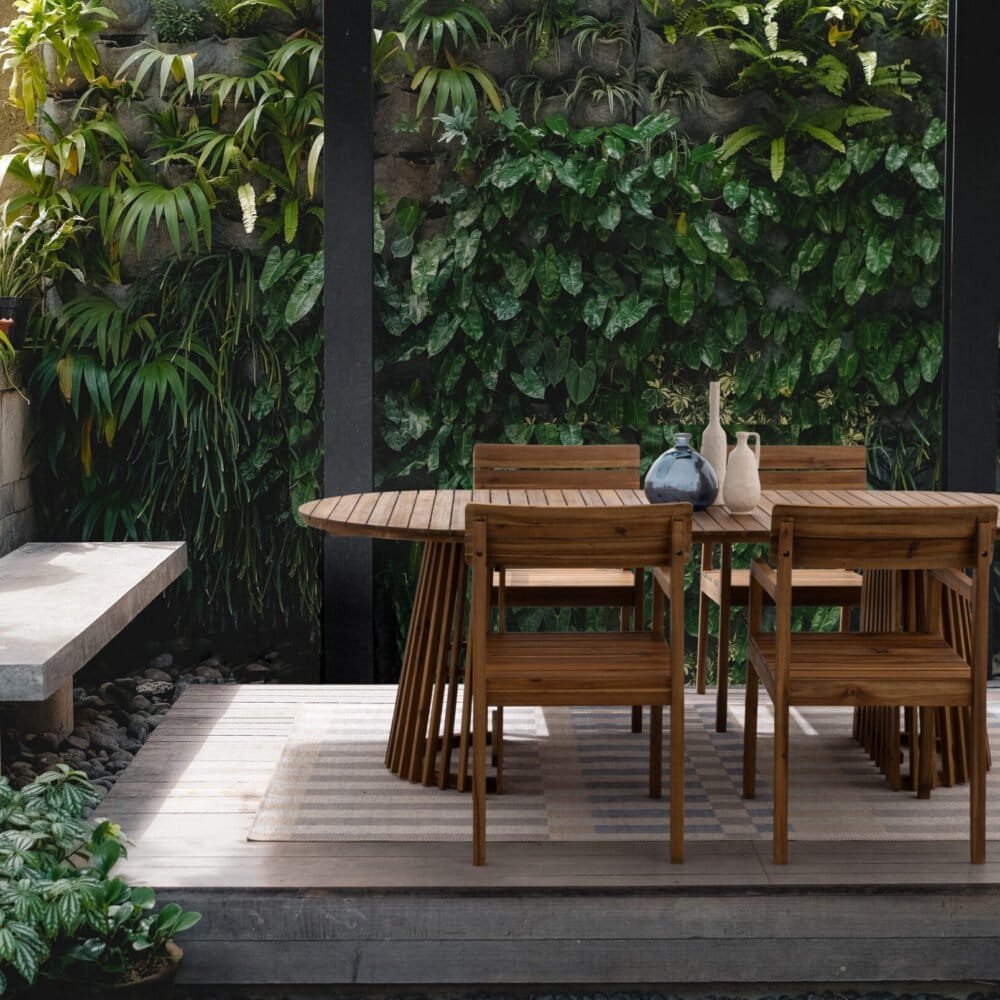 Tavolo in legno e panchine in un giardino pieno di piante verdi e fiori, ambiente naturale e accogliente.