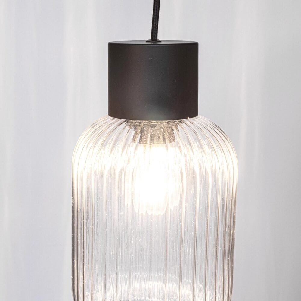 Lampada moderna in vetro trasparente con finitura a righe, inserti eleganti e forma arrotondata, perfetta per ambienti di stile.