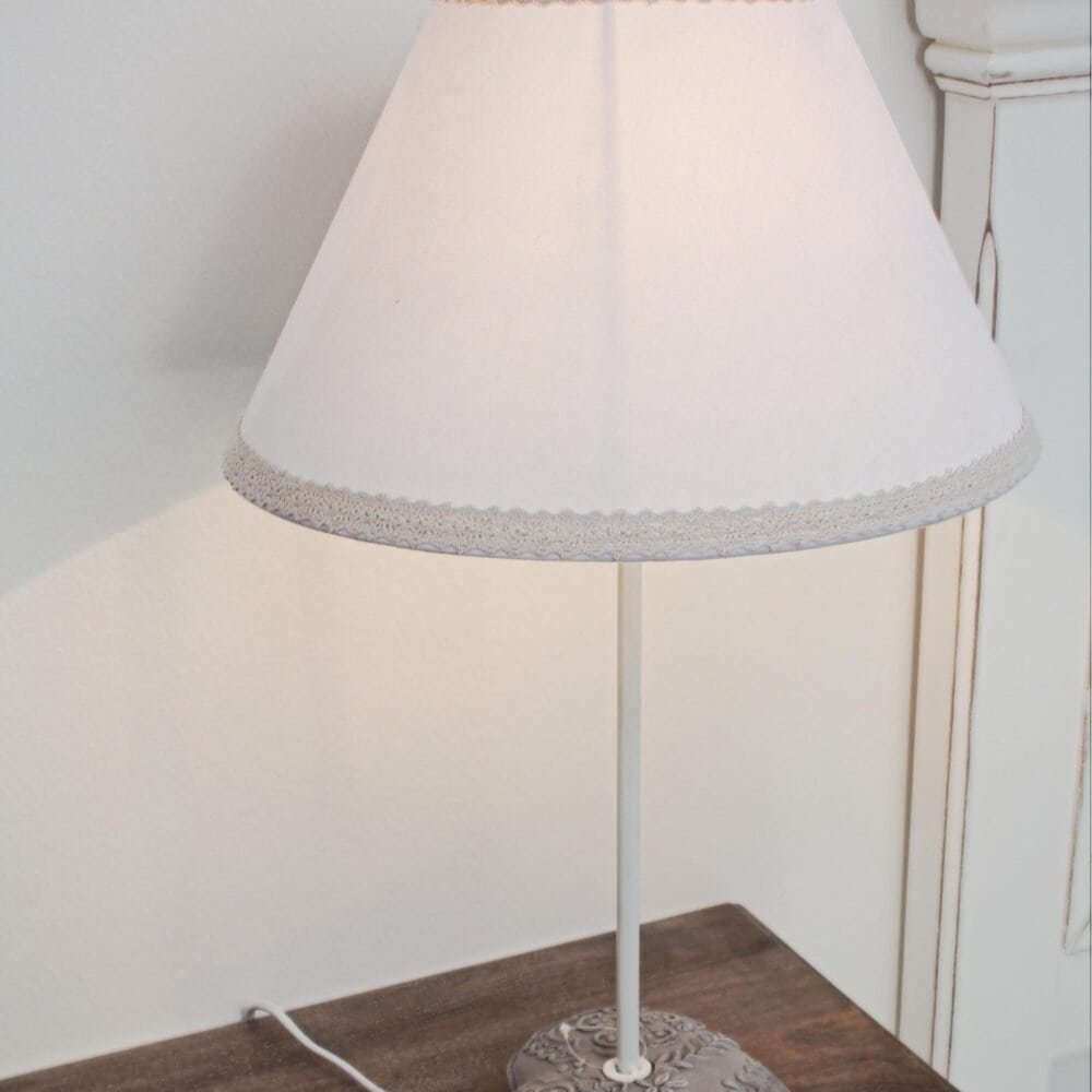 Lampada da tavolo con paralume in tessuto e base in cuoio decorata, perfetta per ambienti eleganti.