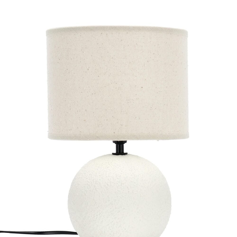 Lampada da tavolo moderna in ceramica bianca con paralume in tessuto neutro.