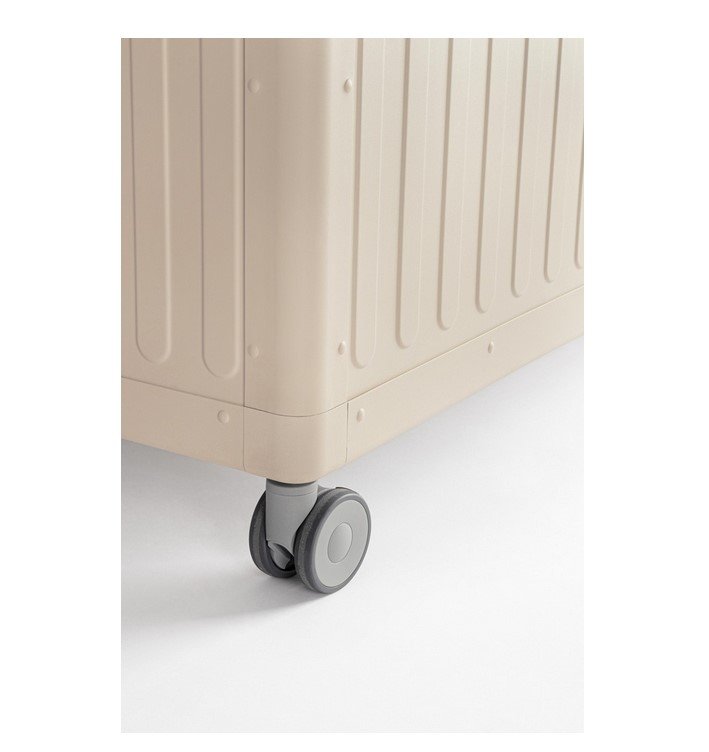 BAULE PCUSC C-RUOTE OCEAN SETA L5 - JOLLYGIUNCO Close-up of the bottom corner of a beige hard-shell suitcase with gray caster wheels on a white floor.
