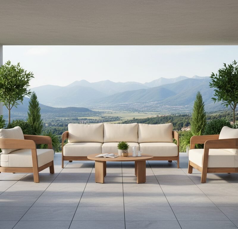 Modern outdoor seating area on a covered terrace with beige cushions and a mountain valley view.