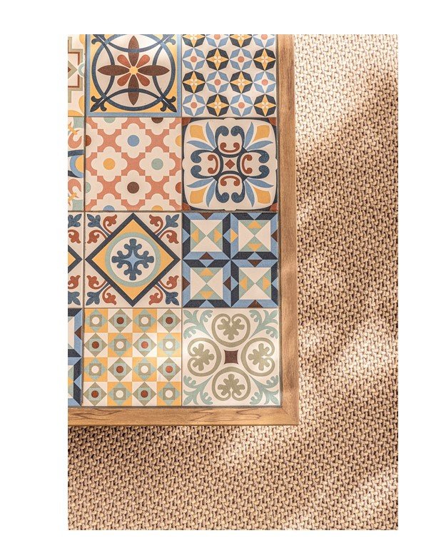 SET SALOTTO ANG C-C KALIMERA DESERT13 - JOLLYGIUNCO Partial view of a wooden-framed mosaic of colorful ceramic tiles resting on a textured beige woven rug.