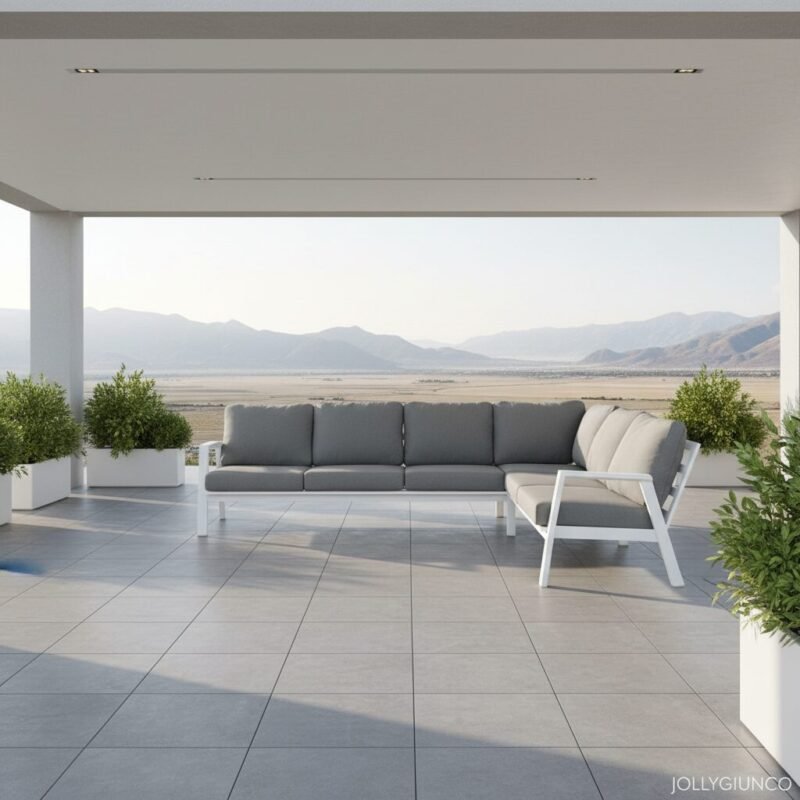 Modern outdoor terrace with a grey-cushioned sectional sofa and white frame, overlooking a desert landscape and distant mountains.