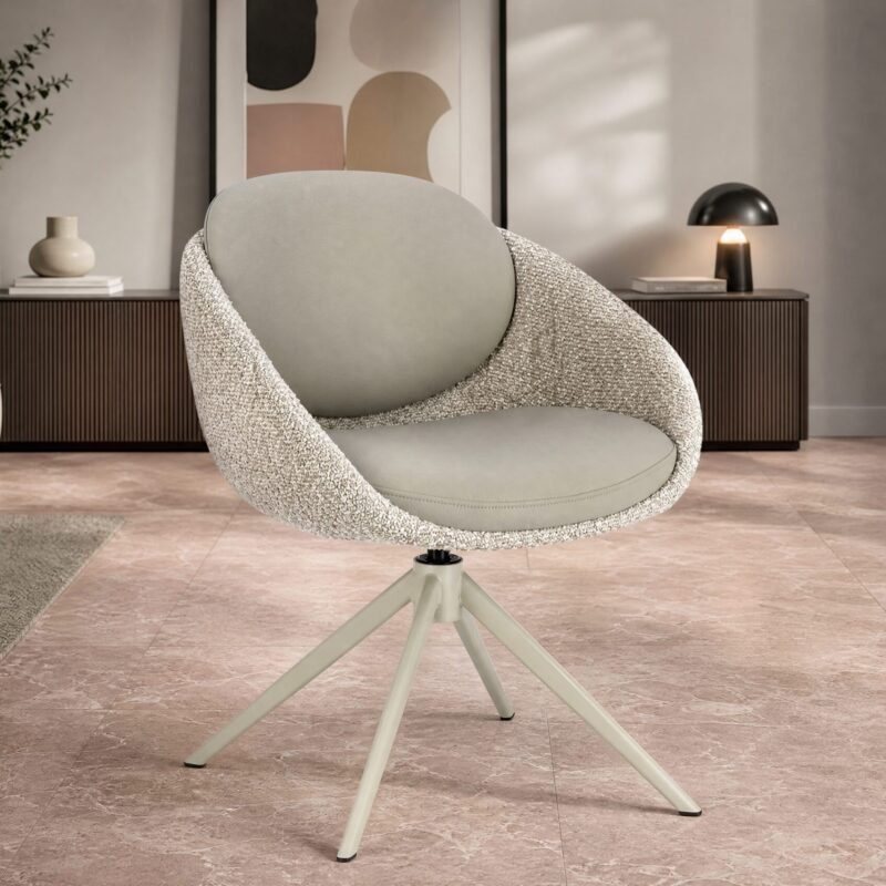 Swiveling lounge chair with textured cream fabric and light grey cushion in a contemporary living room with a wood cabinet and abstract art in the background.