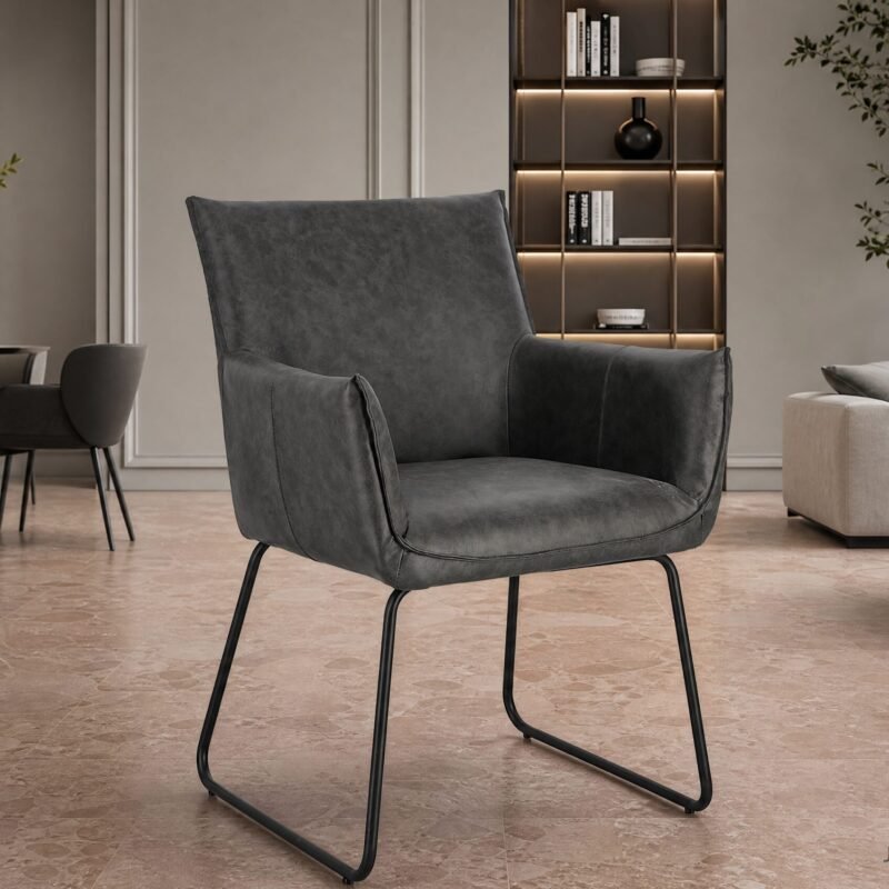Contemporary gray lounge chair with metal legs in a modern living room featuring a bookshelf wall and a potted tree in the background.