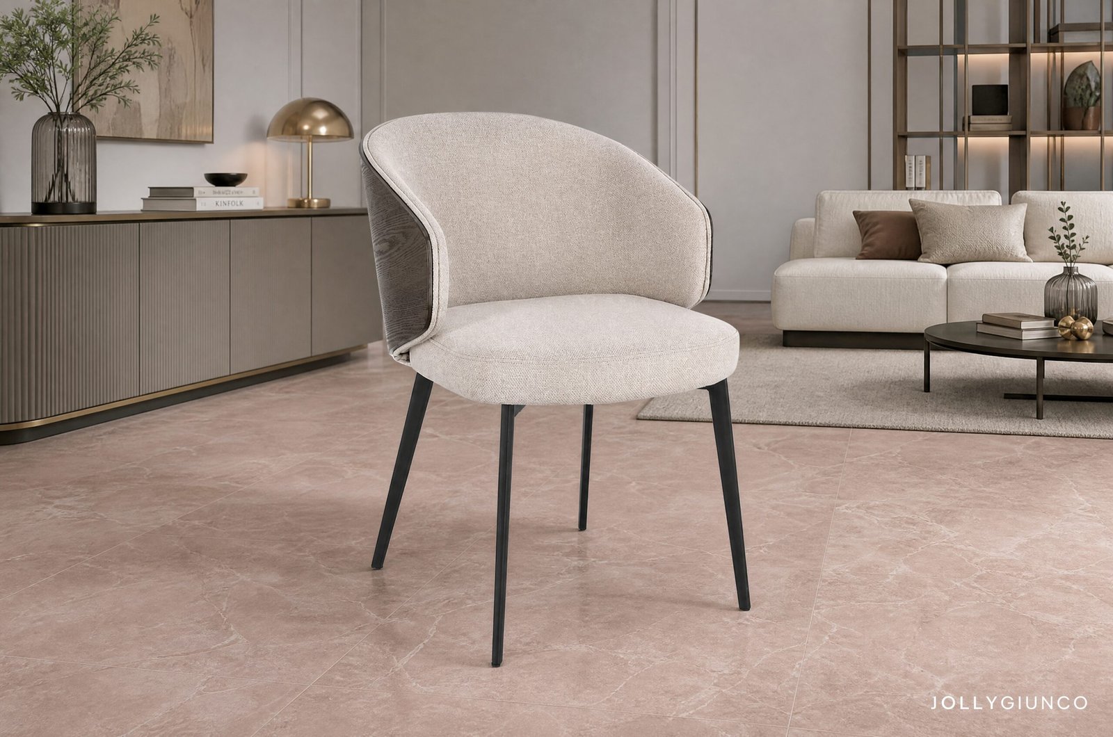 SEDIA C-BR KINSLEY LIGHT10 - JOLLYGIUNCO Beige curved-armchair in a modern living room with a cream sofa, brown cushions, and gold-accent shelving in the background.