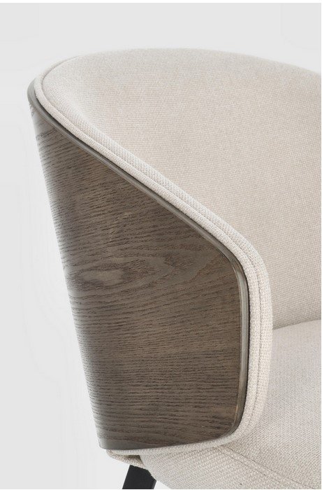 SEDIA C-BR KINSLEY LIGHT4 - JOLLYGIUNCO Close-up of a beige upholstered chair arm with a curved wood-grain panel on the side.