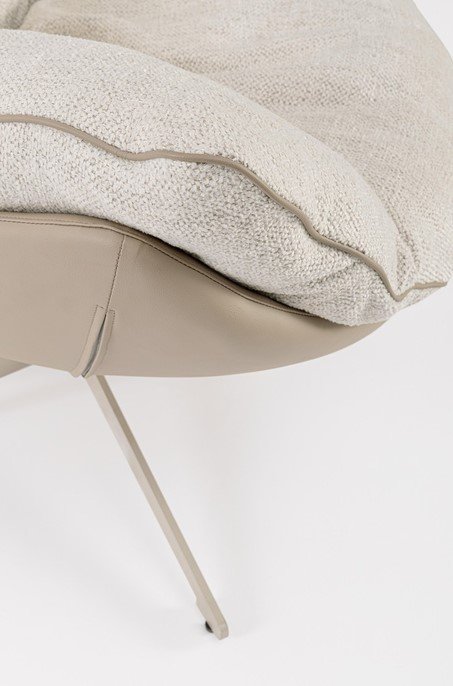 POLTRONA ARMELA BEIGE 7 - JOLLYGIUNCO Close-up of a beige upholstered lounge chair with a fluffy cream cushion on a curved seat edge and angled metal leg.