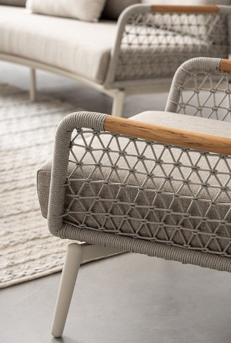 POLTRONA C-C EULERO PELICAN5 - JOLLYGIUNCO Close-up of a gray woven rope lounge chair with a wooden armrest in a modern living room setting.