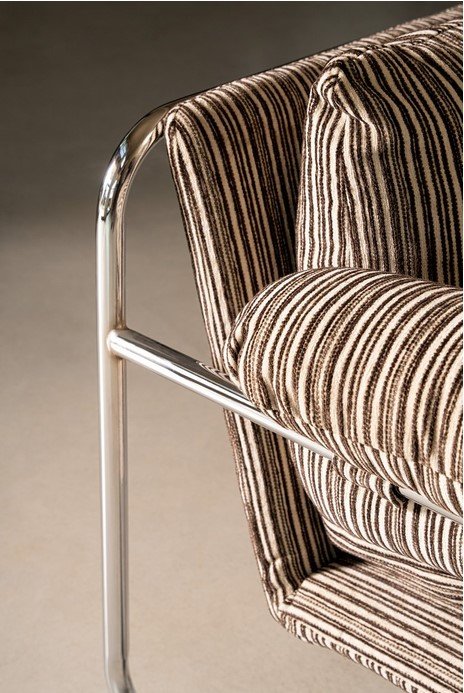 POLTRONA MORVANA RIGHE SAGE6 - JOLLYGIUNCO Close-up of a striped fabric armchair with a shiny chrome frame and rounded armrest reliefs the metal edge against a neutral background.