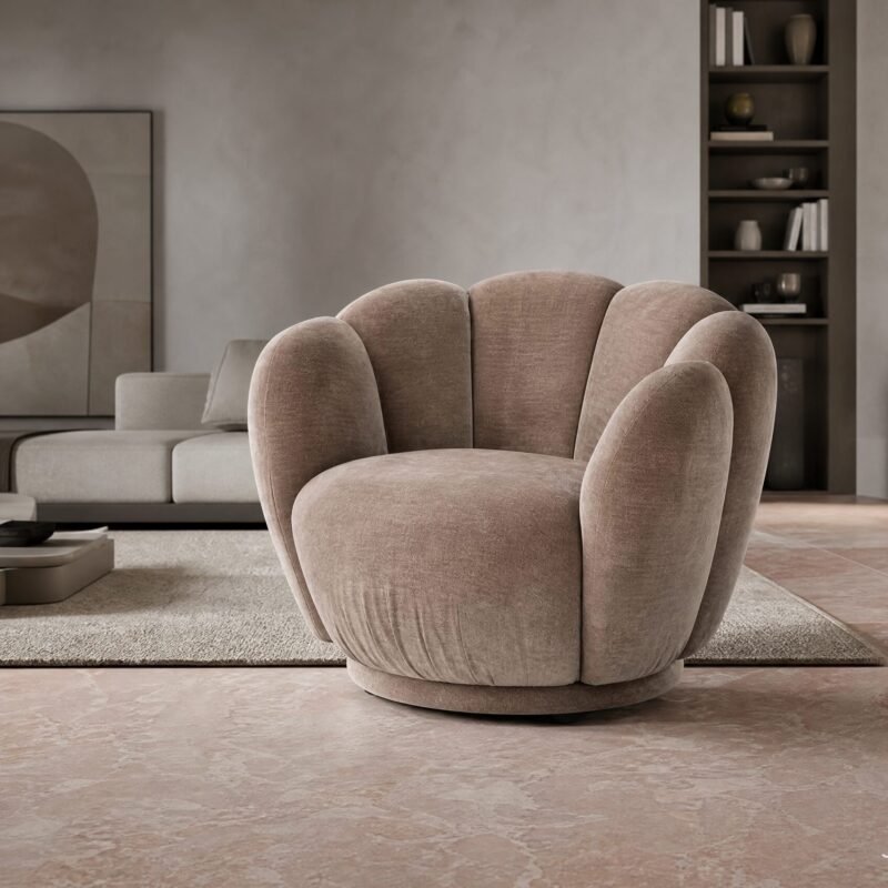 Curved plush beige lounge chair in a modern living room with a bookshelf and abstract artwork on the wall.