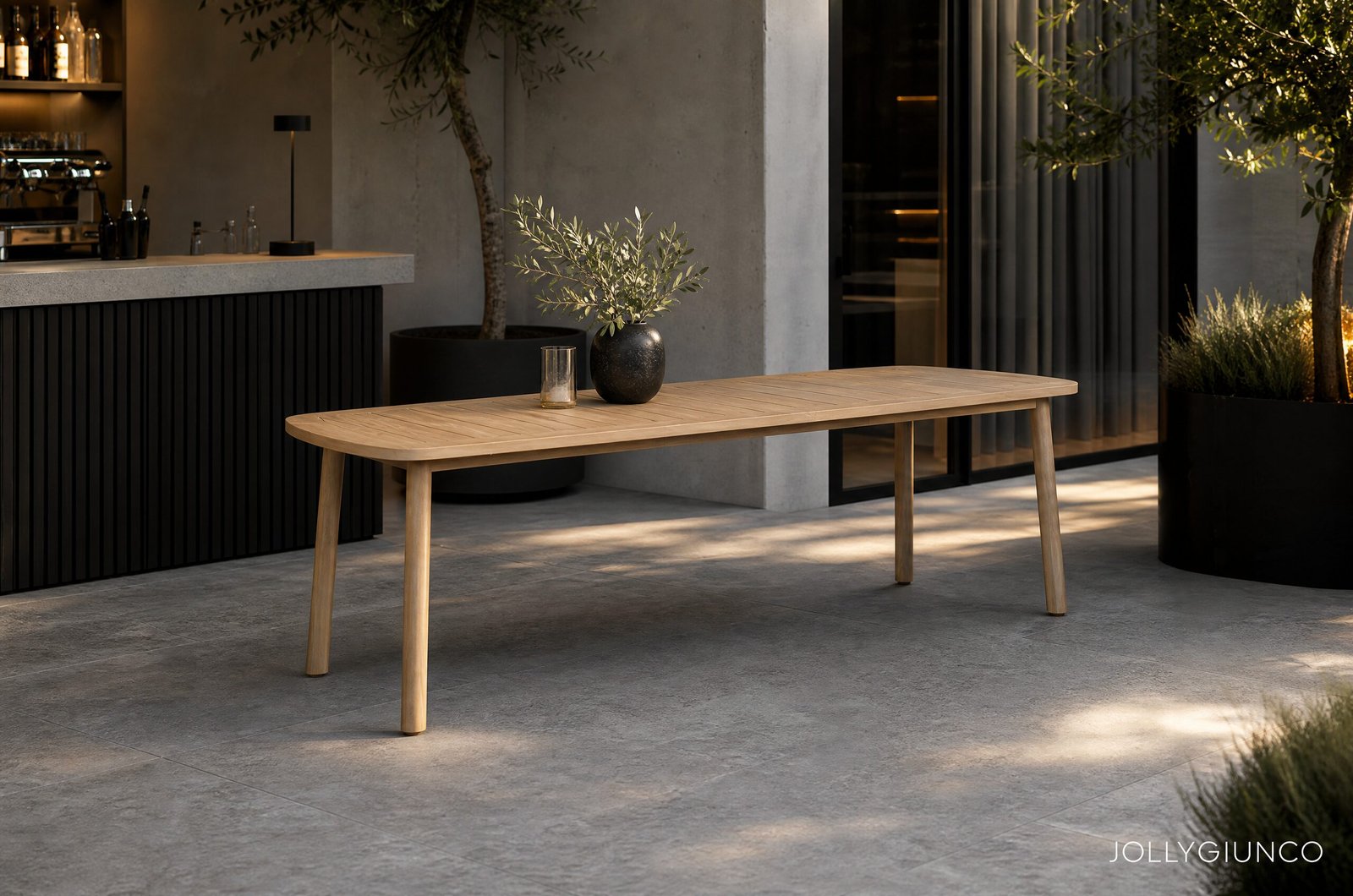 TAVOLO PABLO 240X10010 - JOLLYGIUNCO Outdoor modern cafe terrace with a wooden table, olive branch vase, and glass, against a concrete wall and bar counter on the left while plants frame the scene.