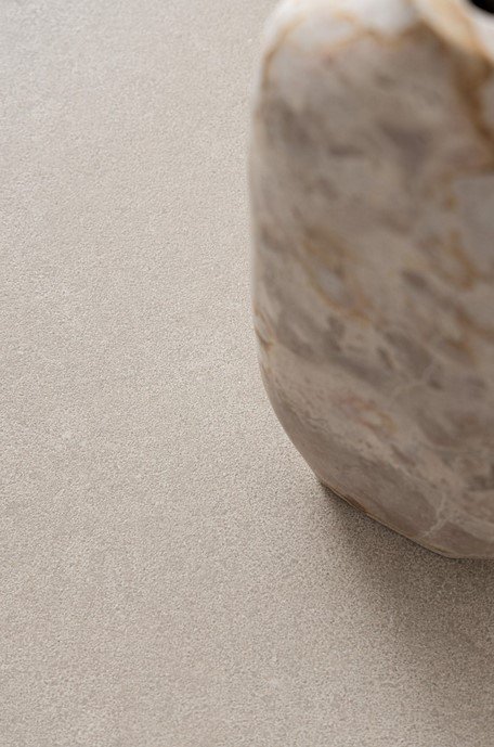 TAVOLO TALETE 135X83X51-72 PELICAN6 - JOLLYGIUNCO Beige smooth rock resting on a light sand-colored surface, occupying the right side of the frame.
